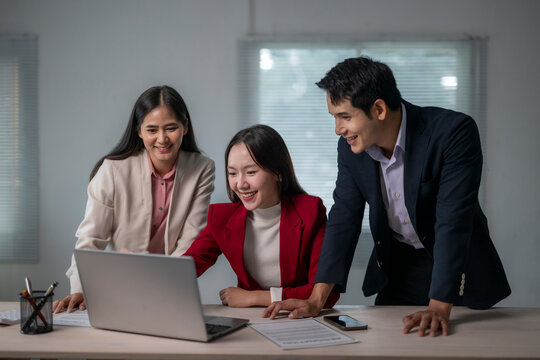 Three people are sitting at a desk with a laptop open