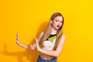 Young stylish woman posing against a bright yellow background, looking curious and gesturing with...