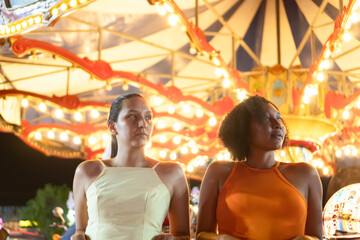 Two friends enjoying a carousel ride at night