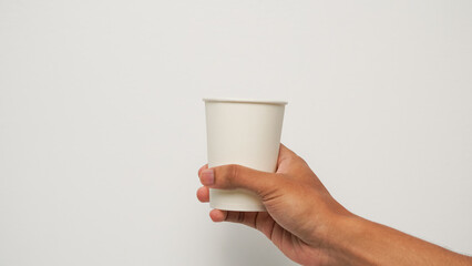 Hand holding a blank white disposable paper cup against a clean white background, ready for drink...