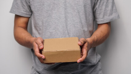 Person's hands holding a small blank brown cardboard box, ideal for delivery or packaging concepts