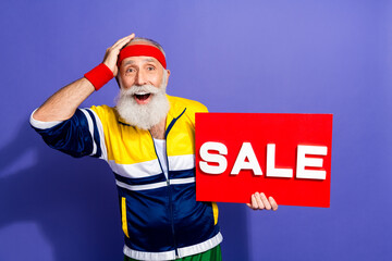 Funny man in retro athletic outfit holding a sale sign with surprise expression against a vibrant...