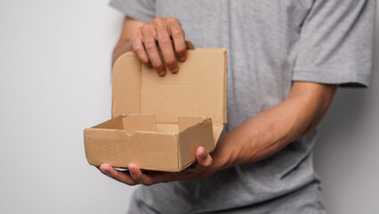 Person holding an open, empty, brown cardboard box with internal dividers, ready for contents