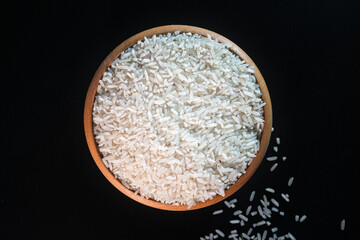 White rice in a wooden bowl set against a black background