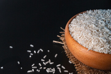 White rice in a wooden bowl set against a black background