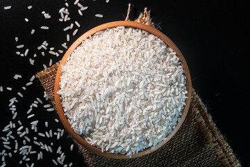 White rice in a wooden bowl set against a black background