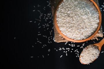 White rice in a wooden bowl set against a black background