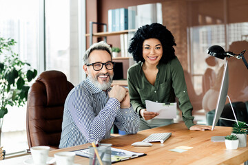 Dynamic office environment showcasing a team collaboration between a cheerful mature professional...