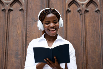 Portrait of happy black African student holding book and studying at the college.