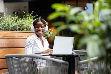 Portrait of elegant black African woman in business suit working on laptop computer in cafe bar.