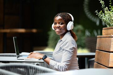 Elegant black African woman in business suit working on laptop computer in cafe bar.