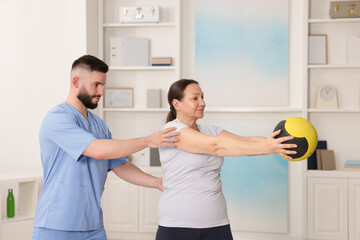 Obraz premium Doctor and patient exercising with medicine ball in clinic