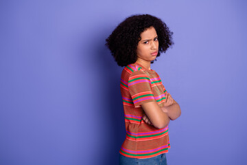 Portrait of a young woman wearing a colorful striped shirt posing on a vibrant purple background...