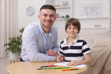 Obraz premium Father teaching his son to draw at table indoors