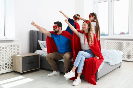 Parents and children in superhero costumes playing at home