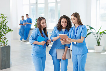 Medical students in uniforms studying together indoors, selective focus