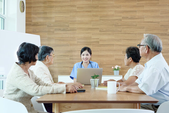Female nurse providing health education to group of elderly women during a wellness meeting, concept of elderly care and community support.