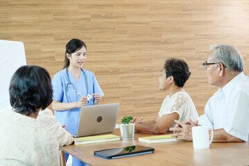 Group of elderly people discussing with female caregiver at a nursing home, reflecting social...