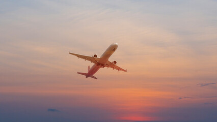commercial airplane flying above over sky in sunset light.