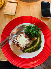 Delicious lasagna with Parmesan, greens, and pesto sauce on an elegant plate