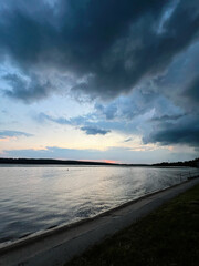 Naklejka premium Dramatic sunset sky over calm river reflecting water with peaceful surroundings