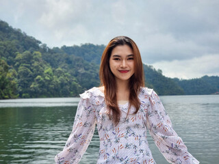 Beautiful female tourist in a casual dress enjoying the view of the lake on a boat with a happy...