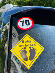 Yellow 'Baby on Board' Sign Displayed on Car with Speed Limit Sticker