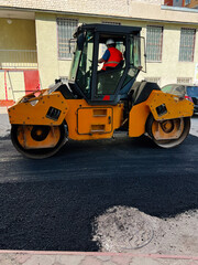 Worker Operating a Yellow Roller in an Urban Construction Area