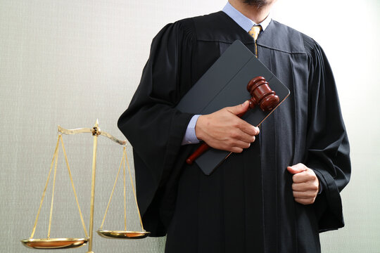 Judge holding gavel and tablet with justice scale in courtroom