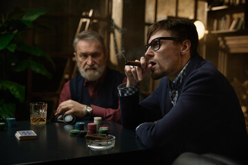 Three men enjoying tense poker game unfolds in a beautifully decorated vintage setting