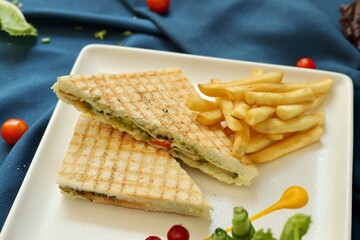 Club sandwich served with french fries on a white plate in a restaurant background 