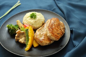 Grilled chicken with vegetables on the side served on a fancy white plate in a restaurant or cafe...