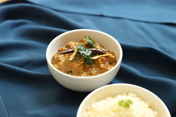 Indian food rice with curry or sabzi served in a white plate in a restaurant background 