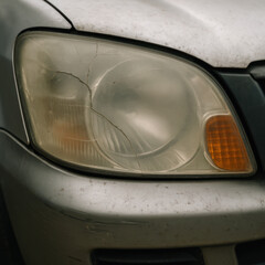 Cracked and Foggy Car Headlight Close-Up  Damaged Vehicle Headlight Lens with Scratches and Wear