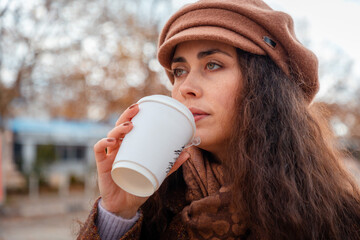 Portrait of Caucasian woman in coat and beret embraces her free time with a coffee in hand. Casual...