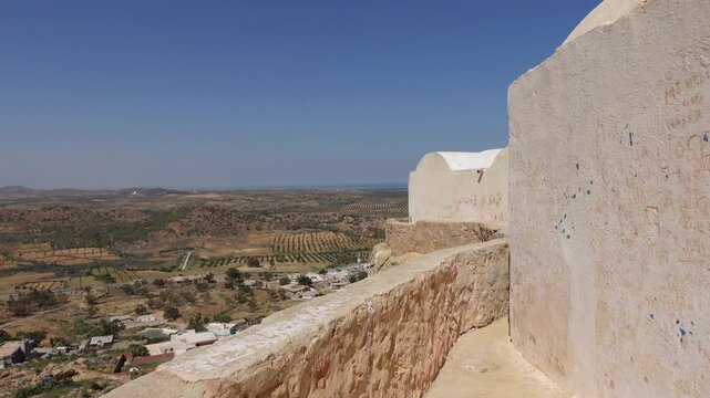 Walking through hilltop Berber village of Takrouna in Tunisia, with splendid views of mountains and olive tree groves
