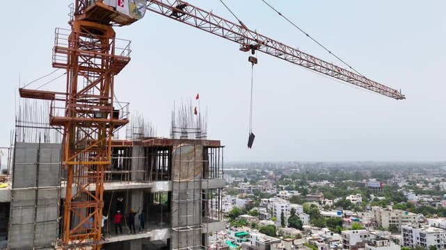Drone aerial shot of crane at construction site with building in background