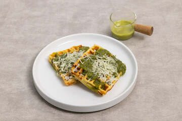 Savory Waffles with Green Sauce and Grated Cheese on White Plate, Served with Extra Sauce