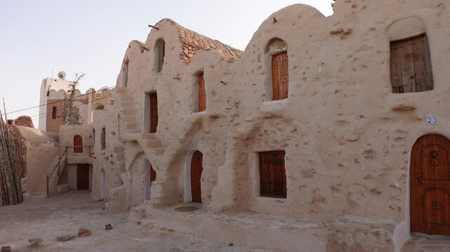 Walking past renovated hotel rooms in classic granary of Ksar Hadada, historic architecture and landmark in Tunisia
