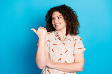 Lovely young woman with curly brown hair making a gesture on a bright blue background during a...