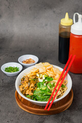 Classic Asian Chicken Noodle Bowl with Fresh Vegetables, Crispy Toppings, and Sauces on a Dark Background
