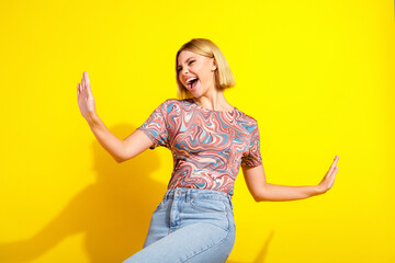 Cheerful young woman confidently posing against bright yellow background showcasing casual style...