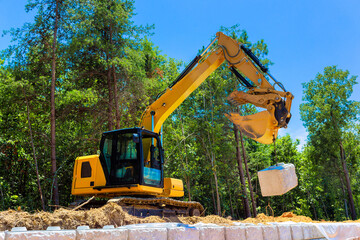 Heavy machinery is actively lifting large stone block during build retaining walls construction...