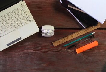 There is a laptop on the table, wireless headphones are lying nearby. Office supplies are visible on the right. Copy space