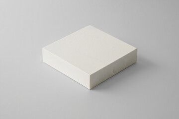 A simple textured off white square block placed on a neutral gray background