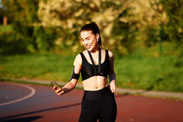 Young sportswoman checking her smartphone during training in a park