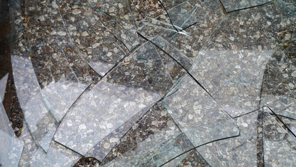 Broken glass with cracks lying on the asphalt close-up, aftermath of an accident, detailing