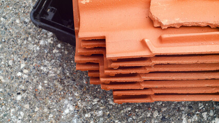 Broken red French roof tiles lie in a pile of rubble