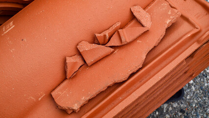 Broken red French roof tiles lie in a pile of rubble