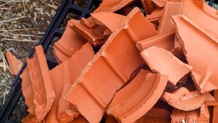 Broken red French roof tiles lie in a pile of rubble